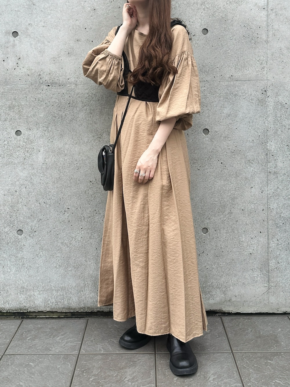 ブラック系のショルダーバッグ、ベージュ系のワンピース、ブラック系のキャップを着用したレディースの秋コーディネートの2枚目の写真