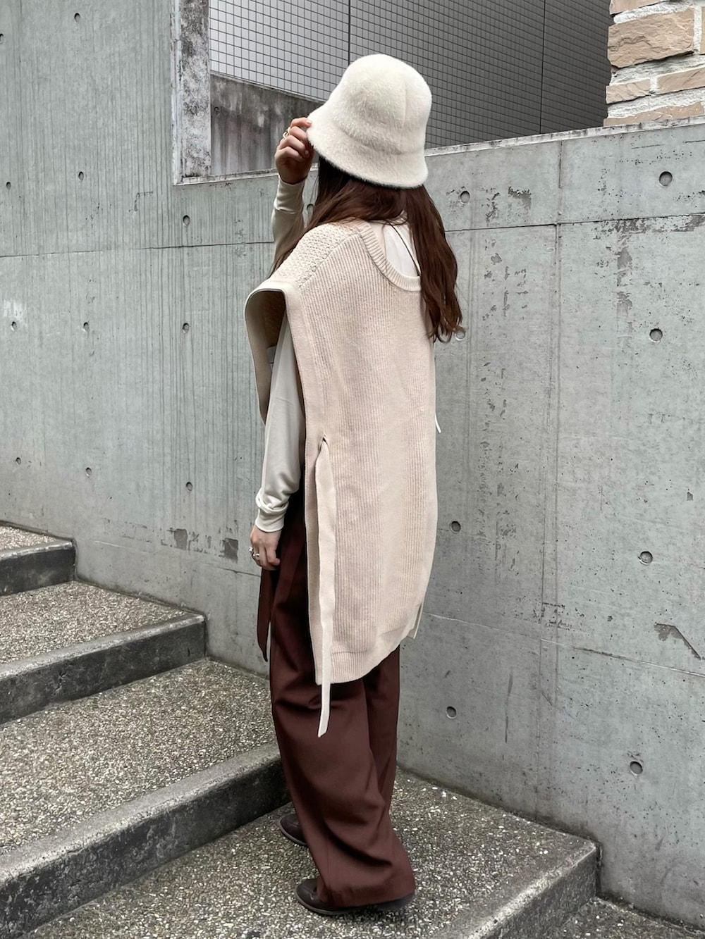 ホワイト系のベスト、ブラウン系のその他パンツ、ホワイト系のショルダーバッグを着用したレディースの秋コーディネートの2枚目の写真