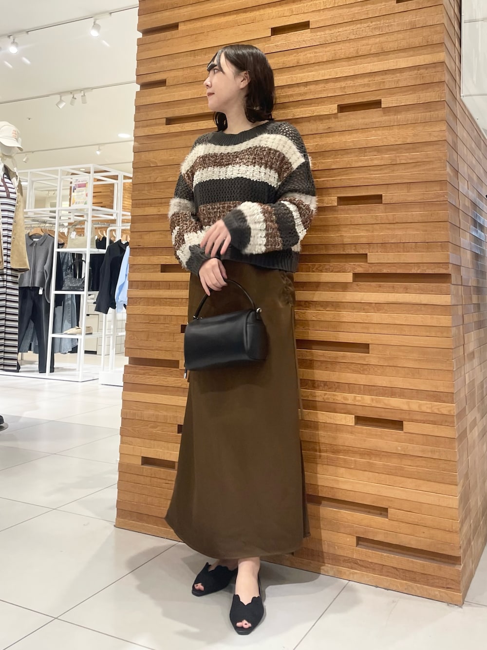 ブラック系のサンダル、ブラック系のニット/セーター、ブラウン系のワンピースを着用したレディースの春コーディネートの3枚目の写真