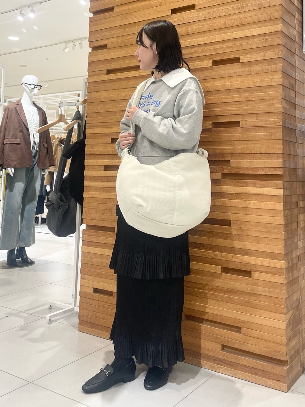 ホワイト系のショルダーバッグ、グレー系のスウェット、ブラック系のスカートを着用したレディースの秋コーディネートの2枚目の写真