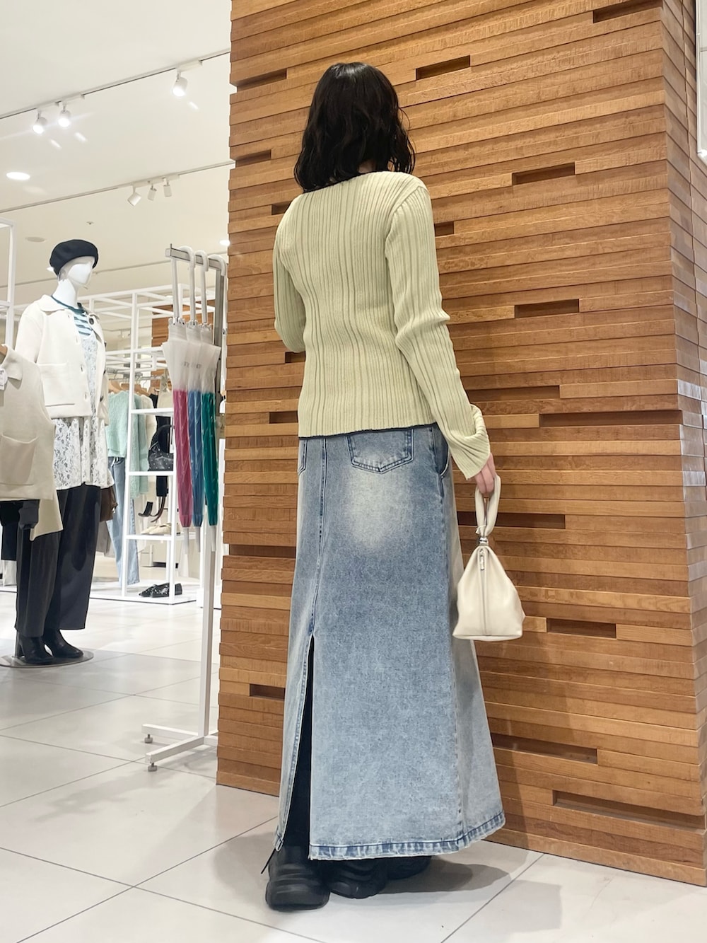 ブラック系のスニーカー、ブルー系のスカート、ベージュ系のニット/セーターを着用したレディースの冬コーディネートの2枚目の写真