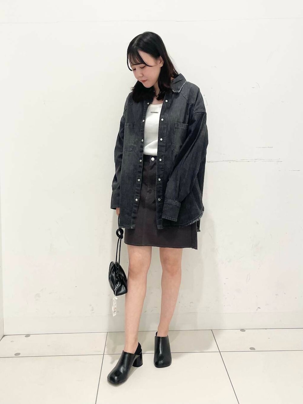 ブラック系のショルダーバッグ、ブラック系のサンダル、グレー系のスカートを着用したレディースの秋コーディネートの2枚目の写真