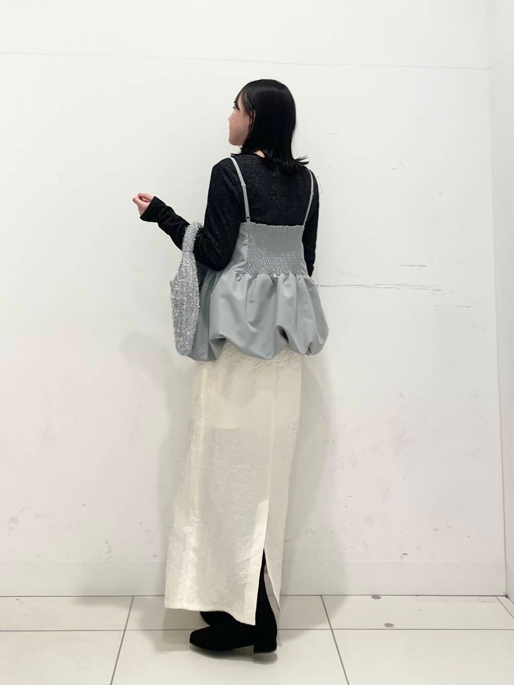 ブラック系のブーツ、シルバー系のトートバッグ、ホワイト系のスカートを着用したレディースの冬コーディネートの2枚目の写真