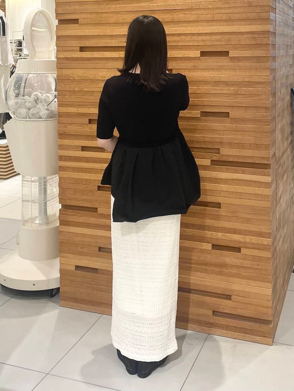 ベージュ系のハンドバッグ、ホワイト系のスカート、ブラック系のニット/セーターを着用したレディースの春コーディネートの3枚目の写真