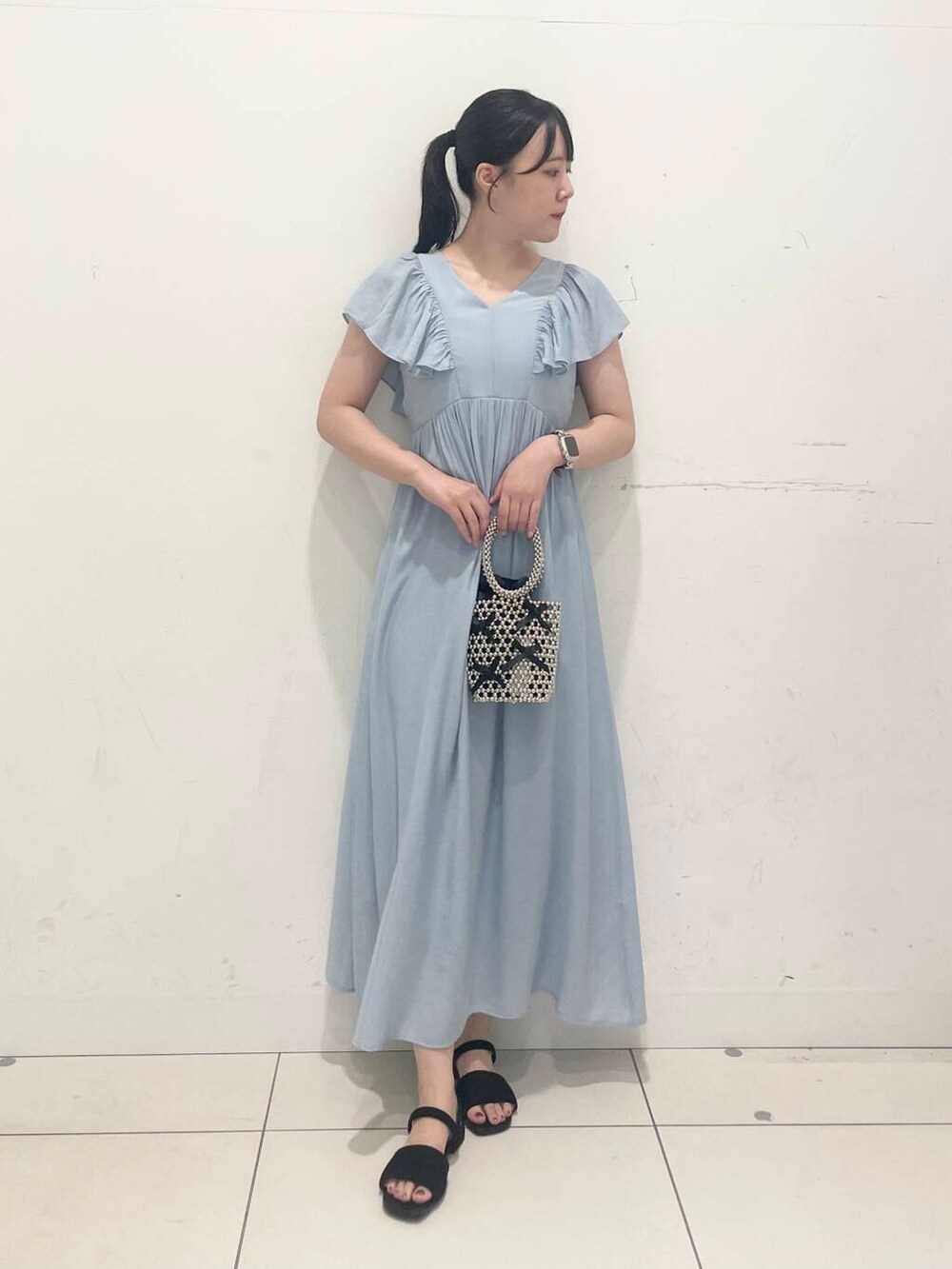 ブラック系のハンドバッグ、ブルー系のワンピース、ブラック系のサンダルを着用したレディースの夏コーディネートの2枚目の写真