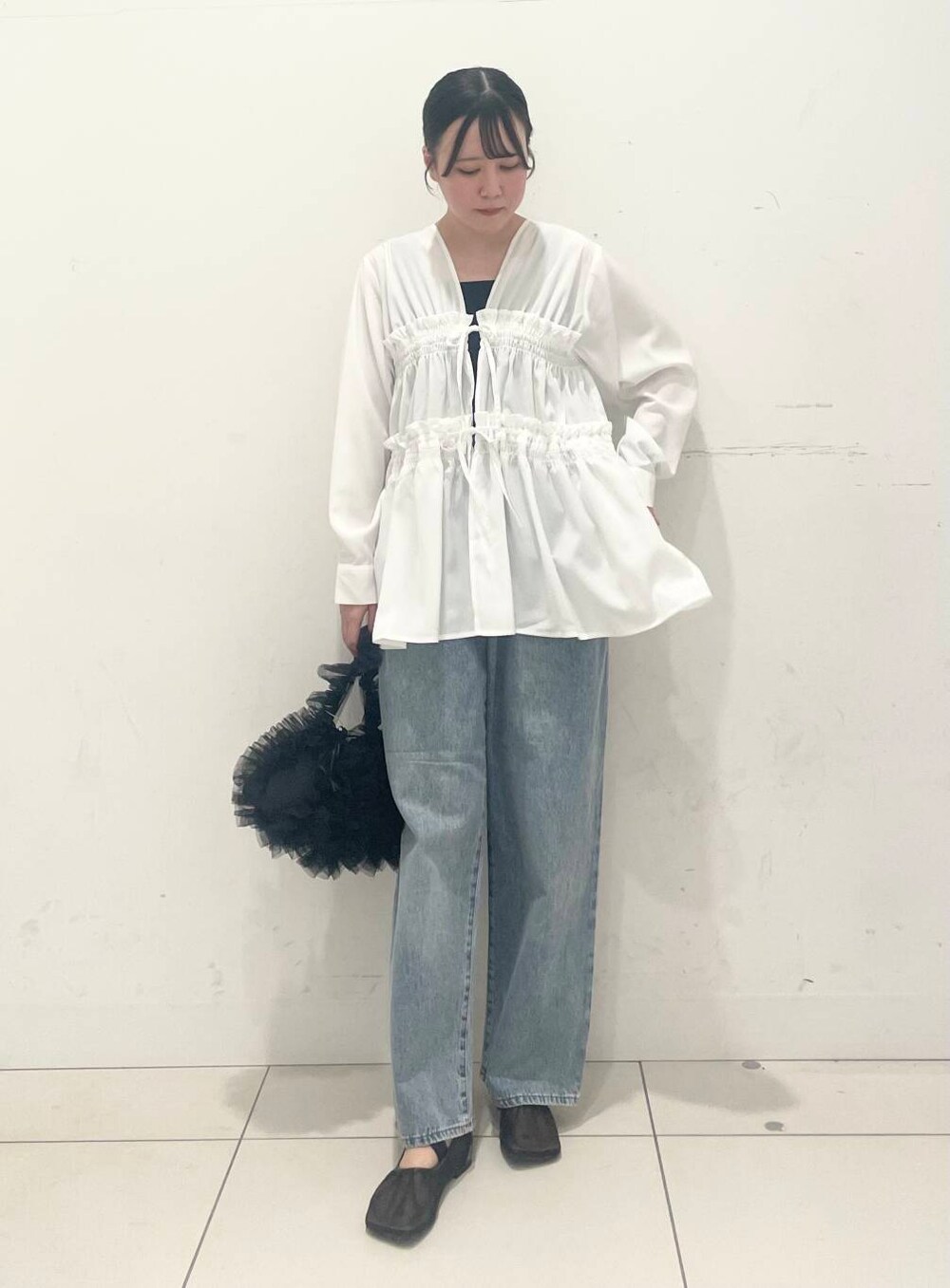 ブルー系のデニムパンツ、ブラック系のハンドバッグ、ブラック系のパンプスを着用したレディースの春コーディネートの3枚目の写真