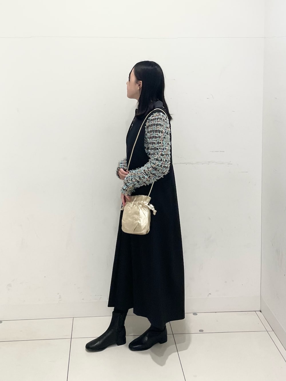 グレー系のニット/セーター、ブラック系のワンピース、ブラック系のブーツを着用したレディースの冬コーディネートの2枚目の写真