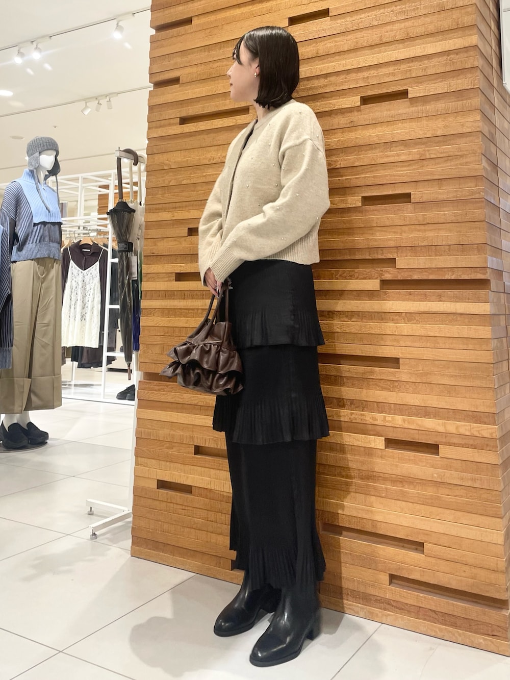 ブラック系のブーツ、ブラック系のスカート、ベージュ系のカーディガン/ボレロを着用したレディースの冬コーディネートの2枚目の写真