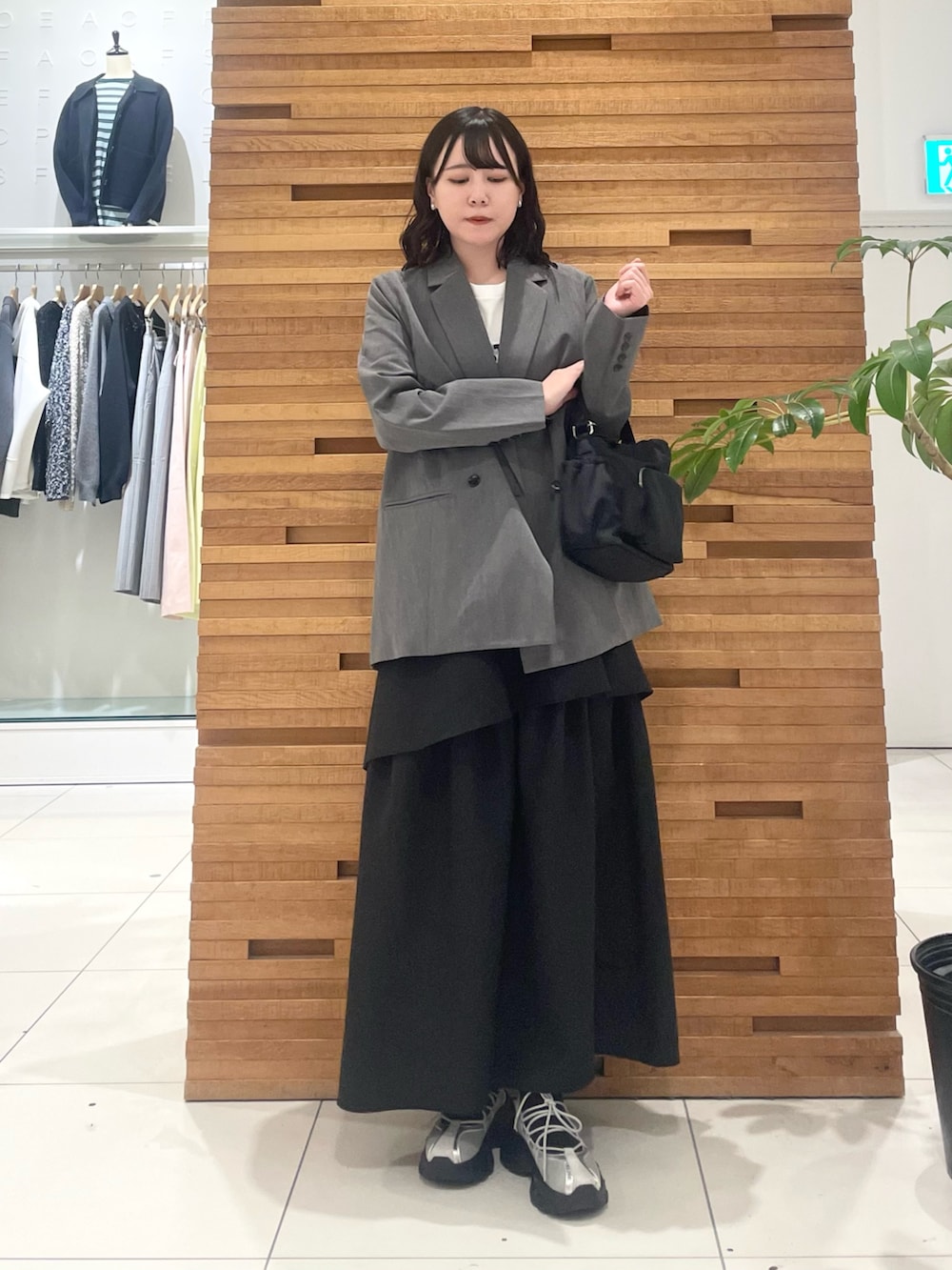 グレー系のスニーカー、ブラック系のスカート、グレー系のテーラードジャケットを着用したレディースの春コーディネートの3枚目の写真