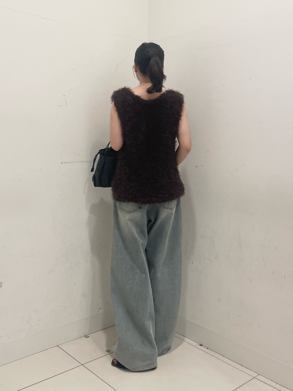 ブラウン系のベスト、ブルー系のデニムパンツ、ブラック系のショルダーバッグを着用したレディースの秋コーディネートの2枚目の写真
