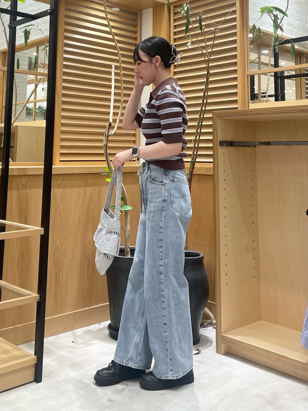 ブラウン系のニット/セーター、シルバー系のショルダーバッグ、ブルー系のデニムパンツを着用したレディースの夏コーディネートの2枚目の写真