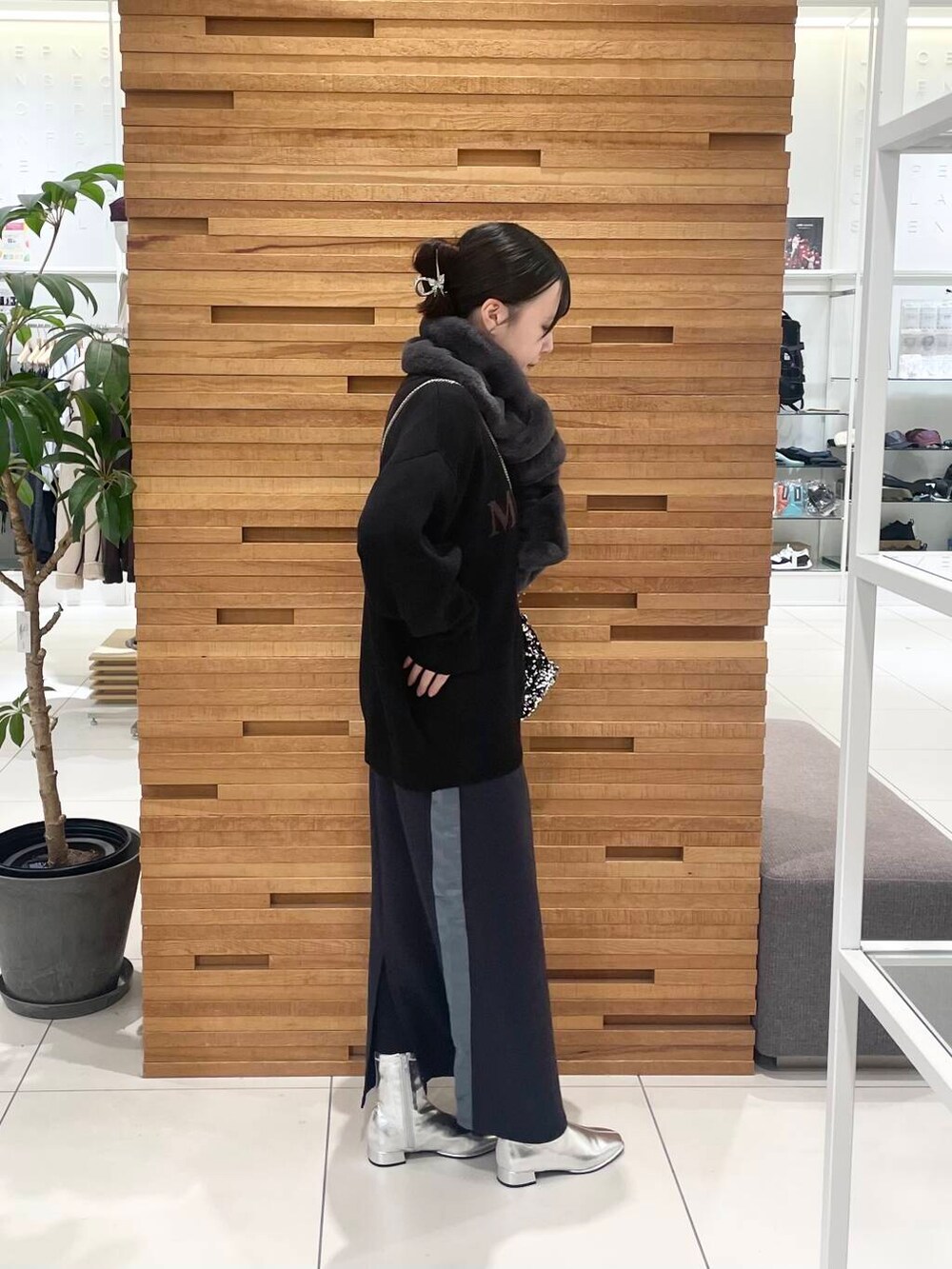 ブラック系のニット/セーター、シルバー系のショルダーバッグ、シルバー系のブーツを着用したレディースの秋コーディネートの2枚目の写真