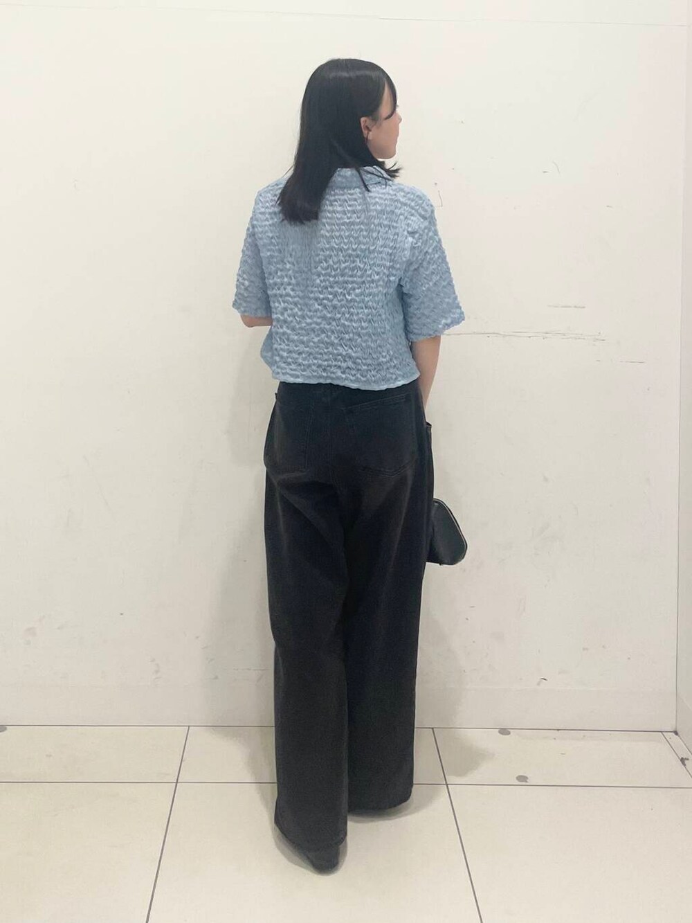 ブラック系のデニムパンツ、ブラック系のボストンバッグ、ブラック系のパンプスを着用したレディースの春コーディネートの2枚目の写真