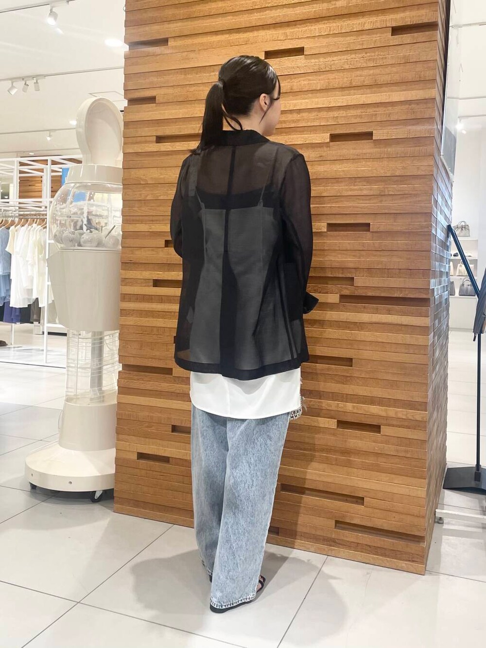 ブルー系のデニムパンツ、グレー系のハンドバッグ、ホワイト系のワンピースを着用したレディースの夏コーディネートの2枚目の写真