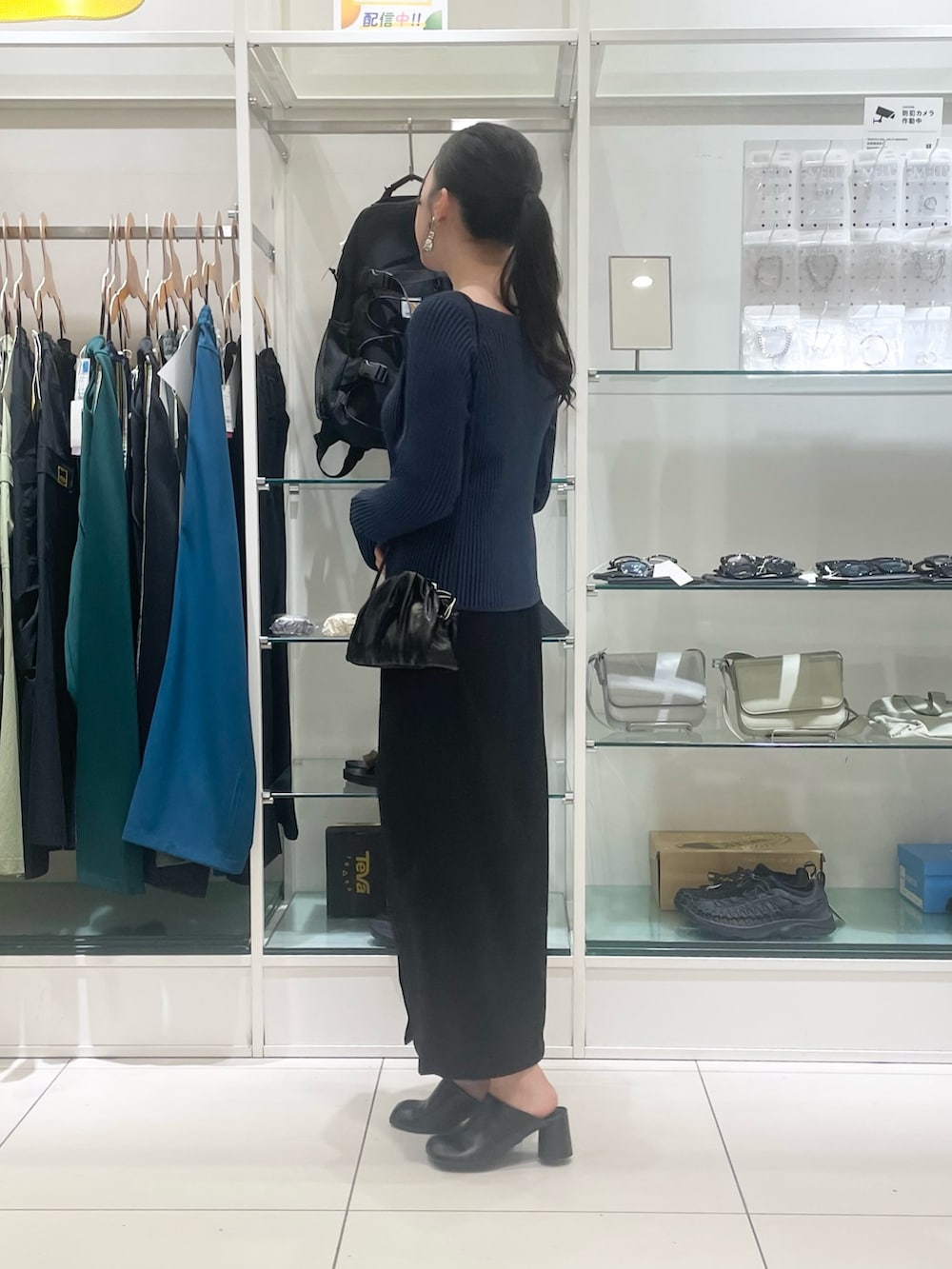 ブルー系のニット/セーター、ブラック系のスカート、ブラック系のショルダーバッグを着用したレディースの夏コーディネートの2枚目の写真