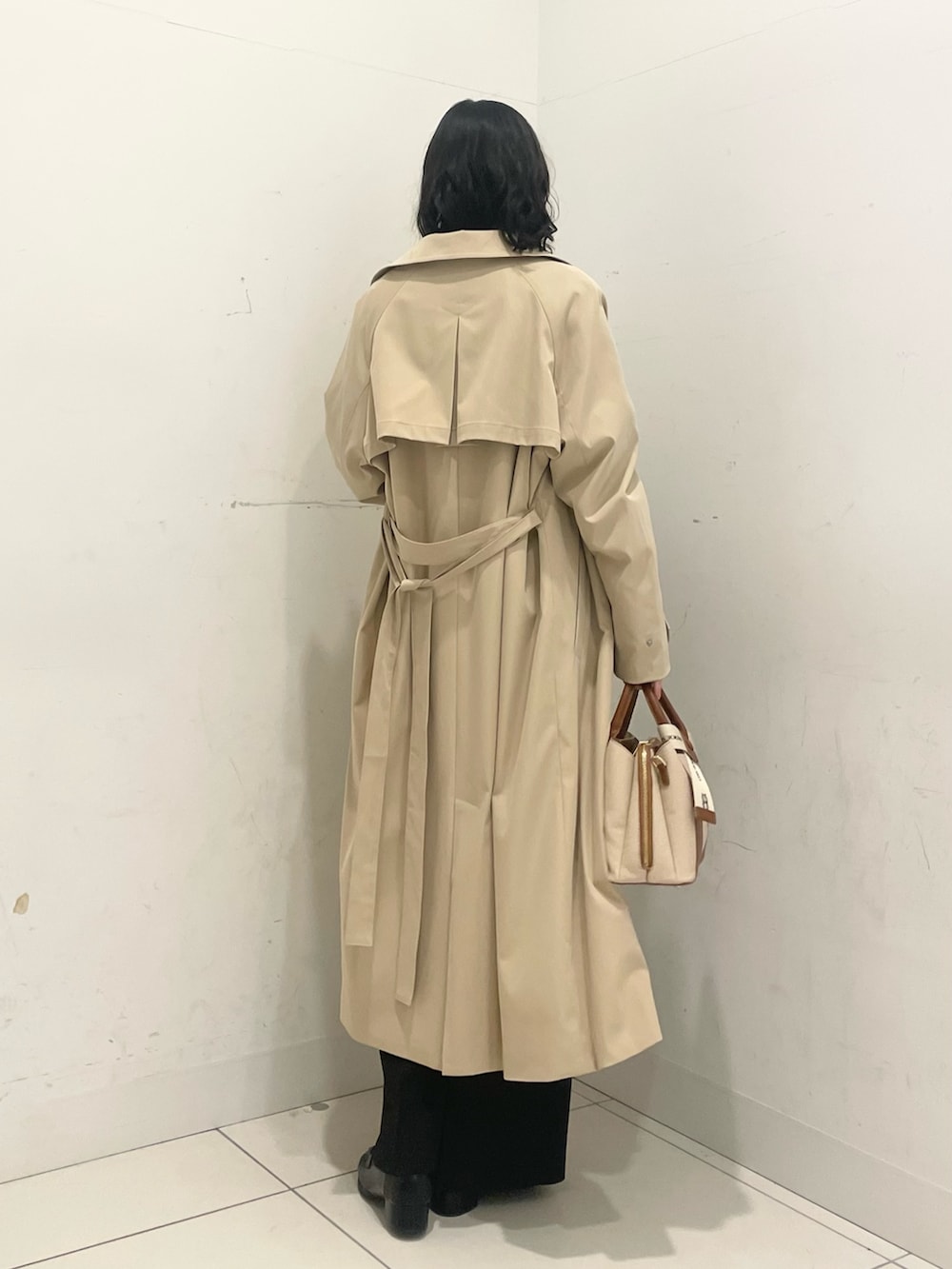 ブラック系のローファー、ブラック系のスラックス、ベージュ系のトレンチコートを着用したレディースの春コーディネートの3枚目の写真