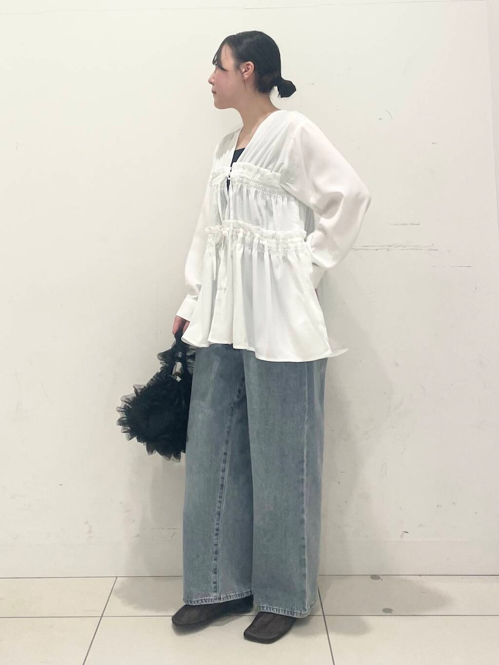 ブルー系のデニムパンツ、ブラック系のハンドバッグ、ブラック系のパンプスを着用したレディースの春コーディネートの2枚目の写真