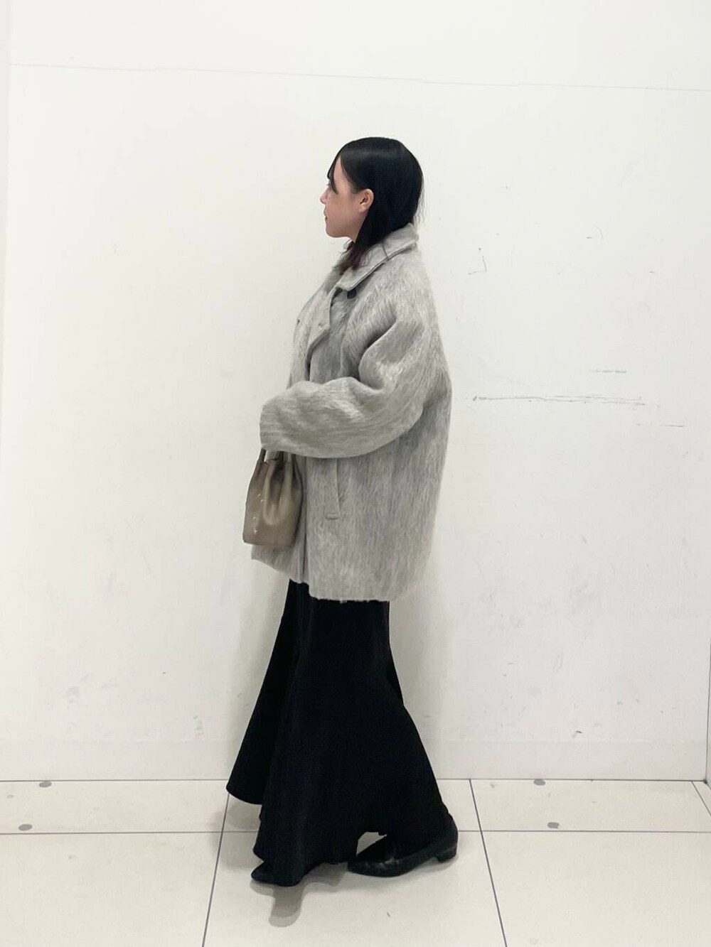 ブラック系のブーツ、ホワイト系のニット/セーター、グレー系のショルダーバッグを着用したレディースの冬コーディネートの2枚目の写真