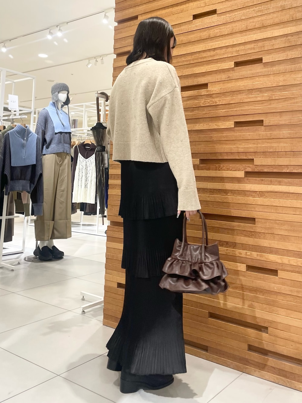 ブラック系のブーツ、ブラック系のスカート、ベージュ系のカーディガン/ボレロを着用したレディースの冬コーディネートの3枚目の写真