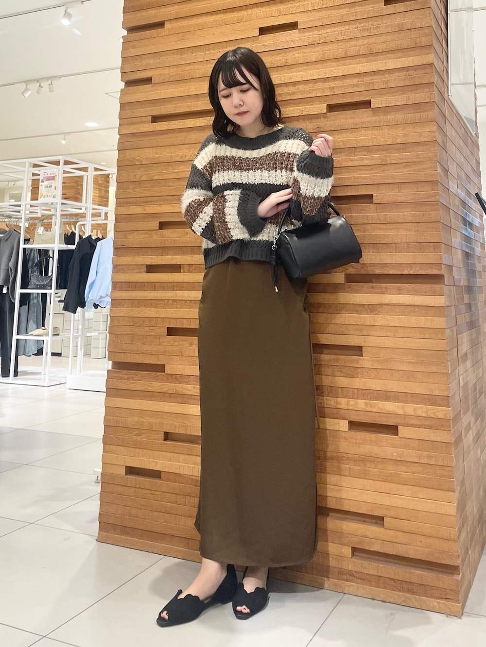 ブラック系のサンダル、ブラック系のニット/セーター、ブラウン系のワンピースを着用したレディースの春コーディネートの2枚目の写真