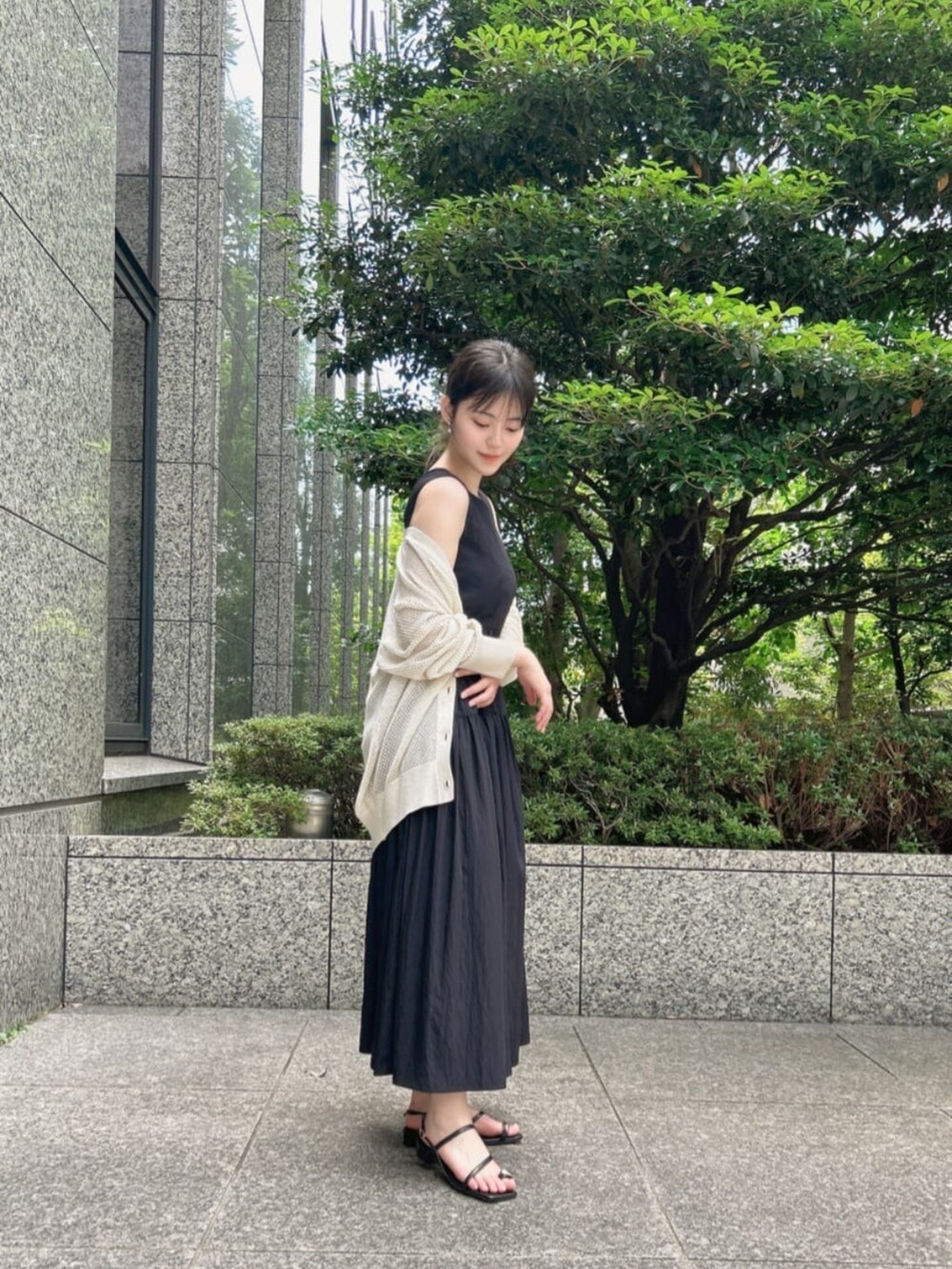 ブラック系のパンプス、ホワイト系のニット/セーター、ブラック系のワンピースを着用したレディースの夏コーディネートの3枚目の写真