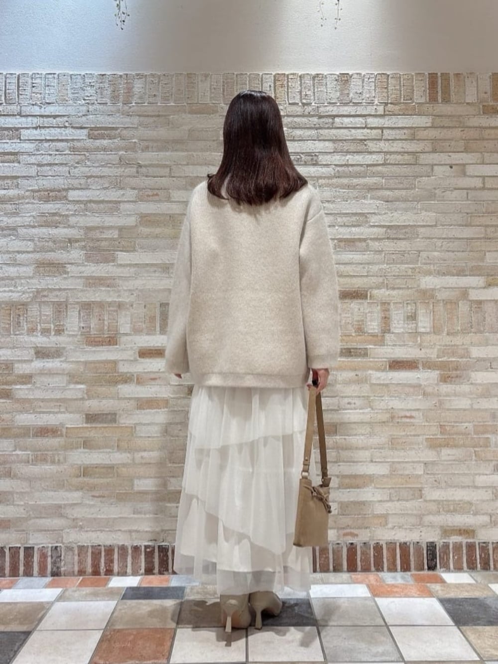 ベージュ系のショルダーバッグ、ホワイト系のスカート、ホワイト系のカーディガン/ボレロを着用したレディースの冬コーディネートの3枚目の写真