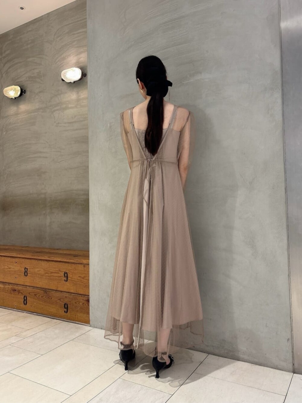 ブラック系のショルダーバッグ、ブラック系のパンプス、ベージュ系のワンピースを着用したレディースの秋コーディネートの3枚目の写真