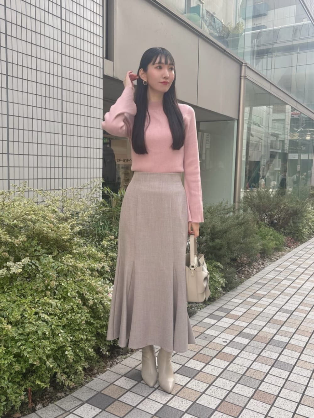 ピンク系のニット/セーター、ブラウン系のスカート、ベージュ系のショルダーバッグを着用したレディースの冬コーディネートの2枚目の写真