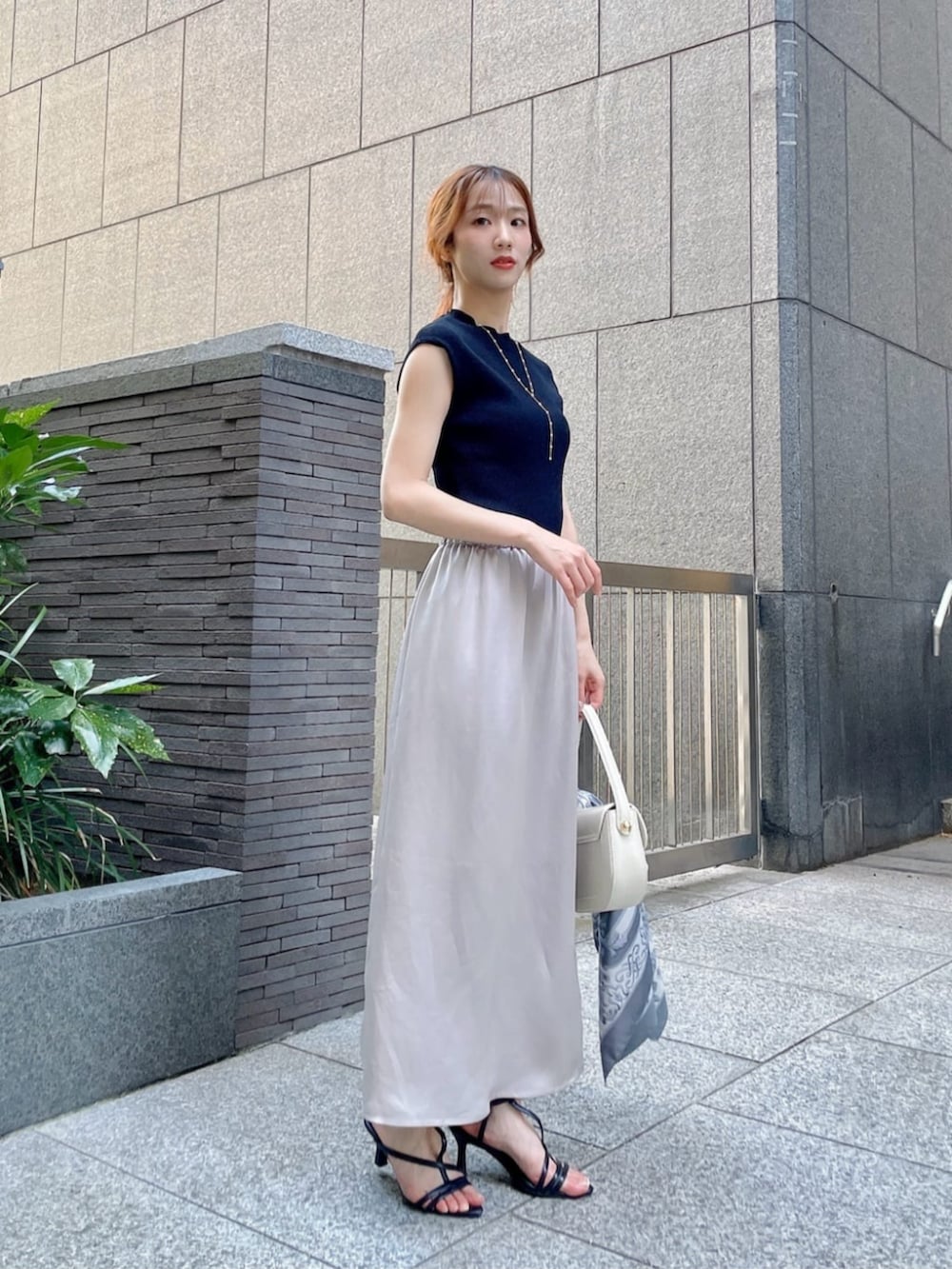 ブラック系のパンプス、ブラック系のニット/セーター、ベージュ系のスカートを着用したレディースの夏コーディネートの3枚目の写真