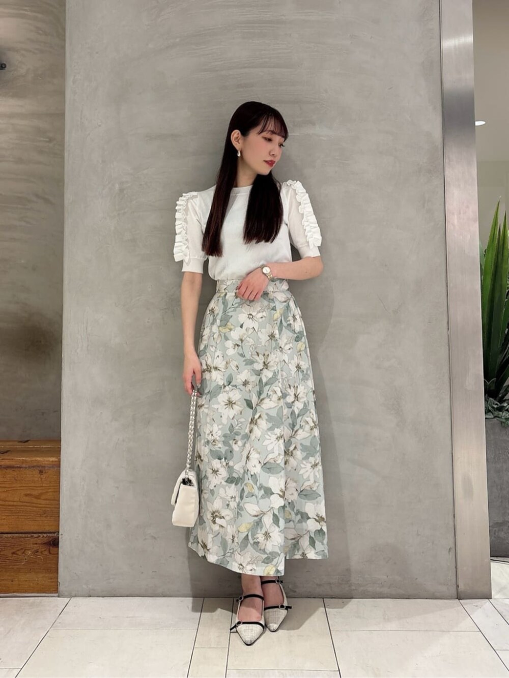 グリーン系のスカート、ホワイト系のショルダーバッグ、ホワイト系のニット/セーターを着用したレディースの春コーディネートの2枚目の写真