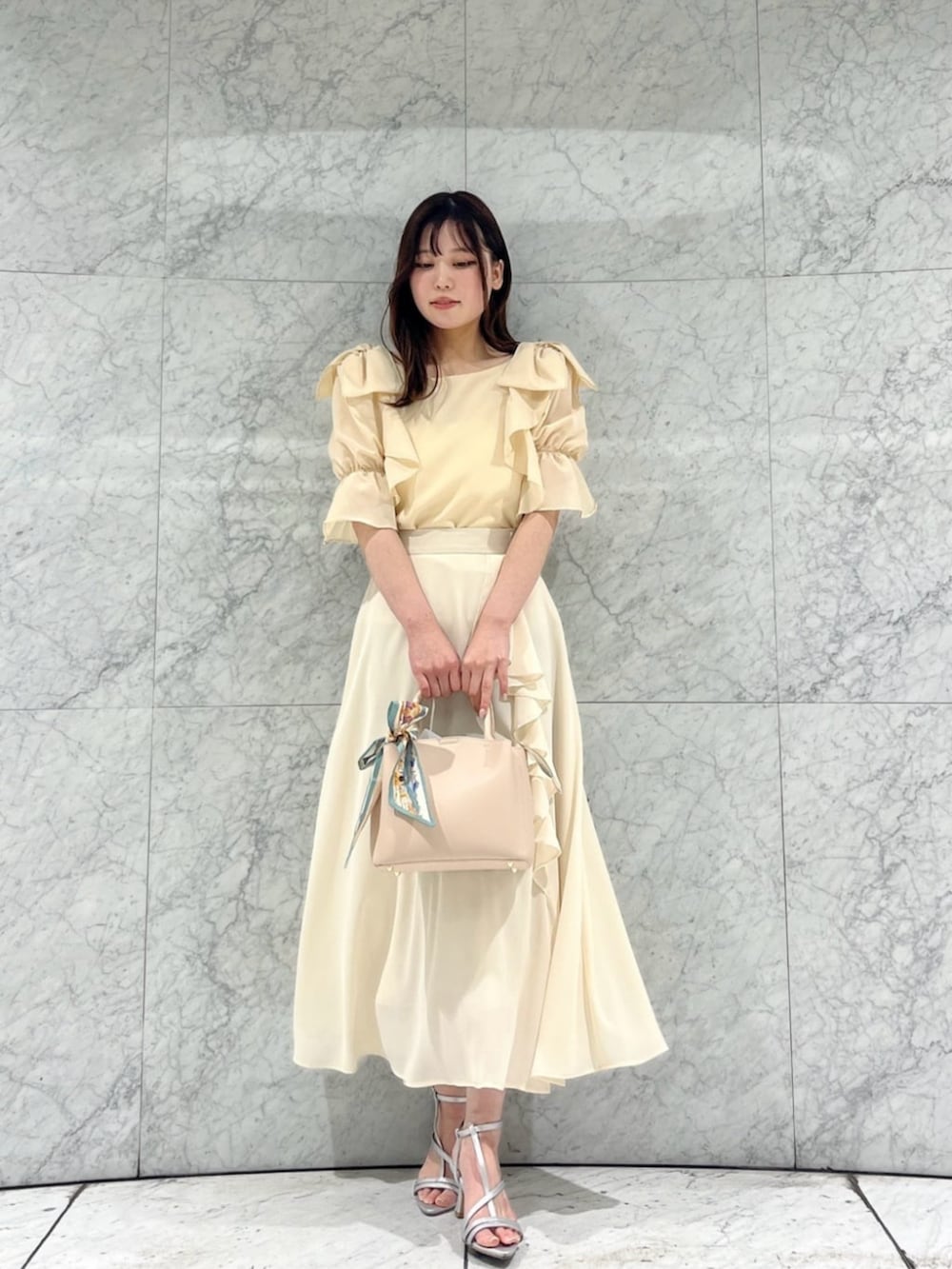シルバー系のパンプス、ホワイト系のカーディガン/ボレロ、ベージュ系のトートバッグを着用したレディースの春コーディネートの2枚目の写真