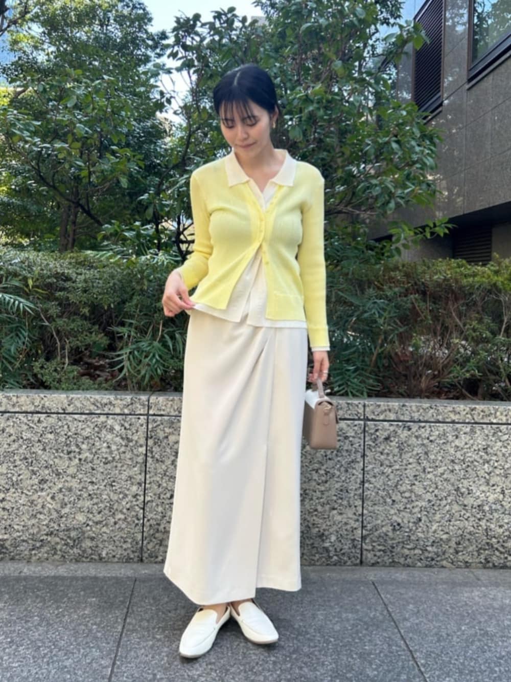 イエロー系のニット/セーター、ホワイト系のスカートを着用したレディースの春コーディネートの2枚目の写真