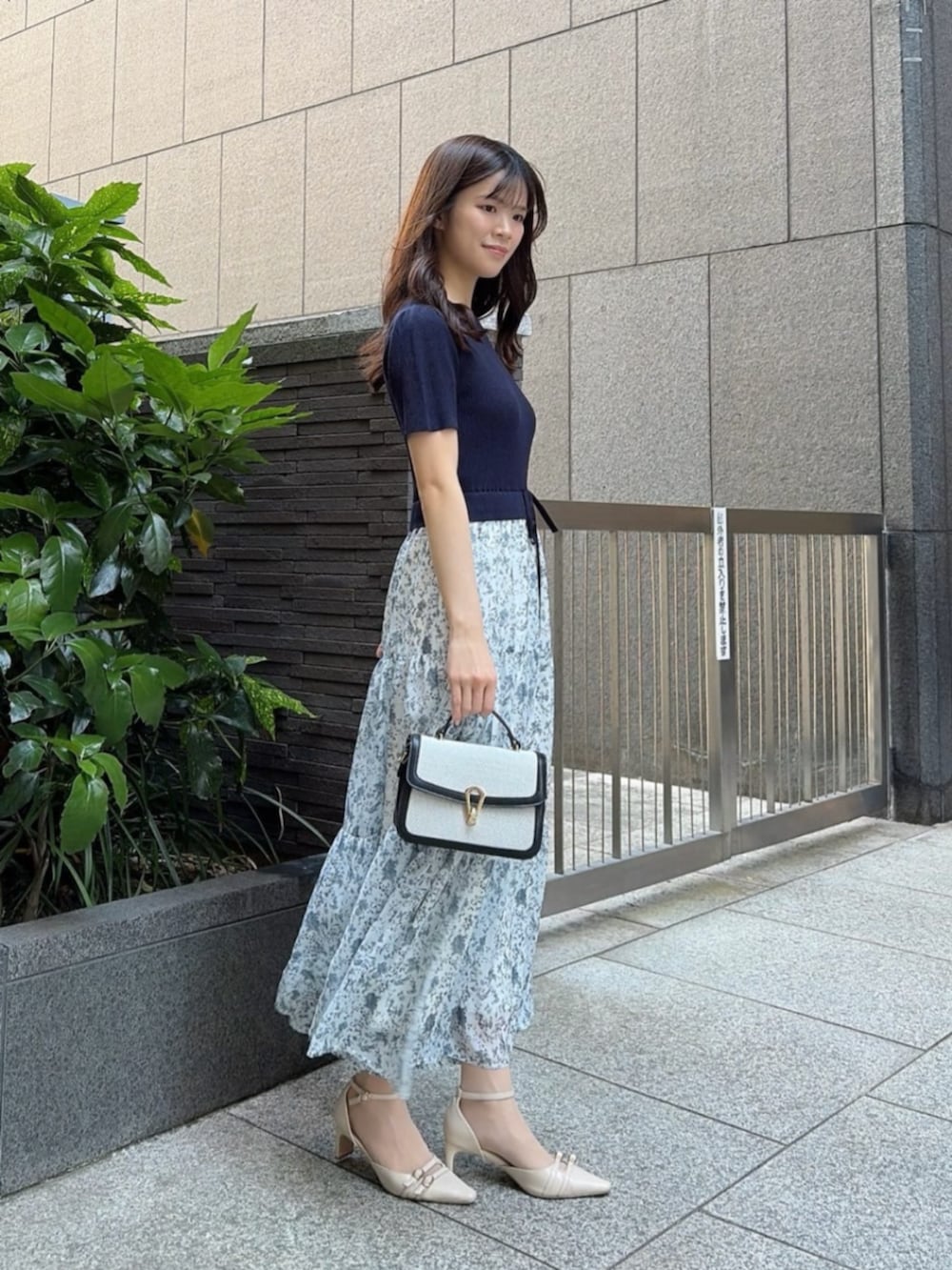 ベージュ系のパンプス、ブラック系のショルダーバッグ、ブルー系のワンピースを着用したレディースの春コーディネートの2枚目の写真