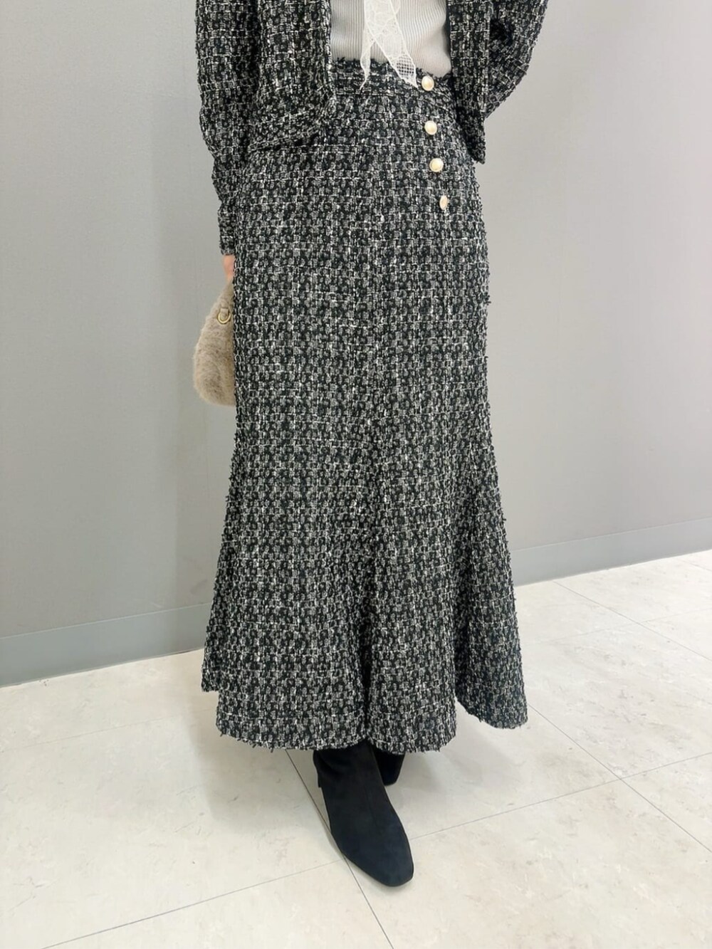 ベージュ系のハンドバッグ、ブラック系のテーラードジャケット、ブラック系のスカートを着用したレディースの秋コーディネートの4枚目の写真