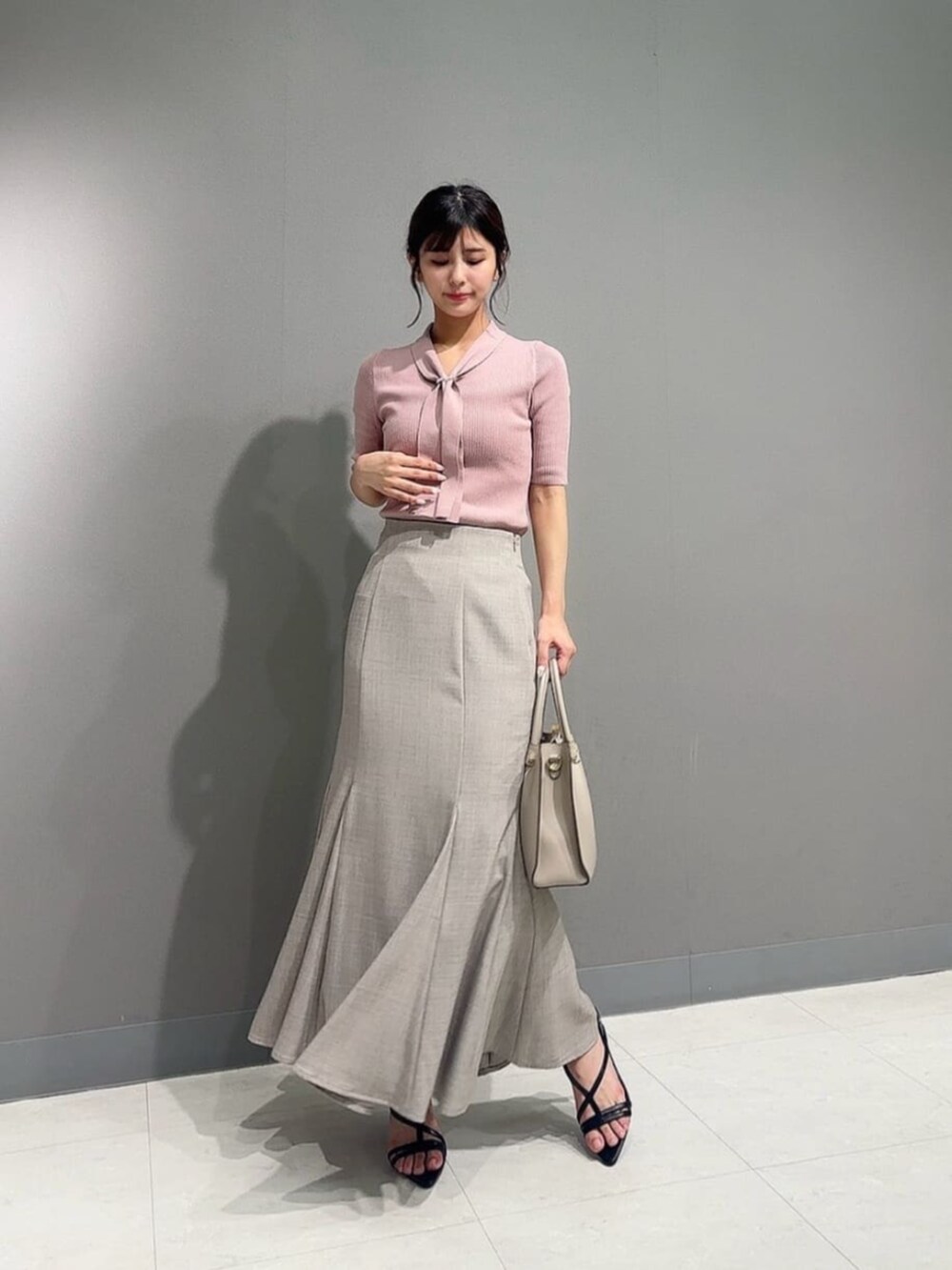 ブラウン系のスカート、ブラック系のパンプス、ピンク系のニット/セーターを着用したレディースの夏コーディネートの2枚目の写真