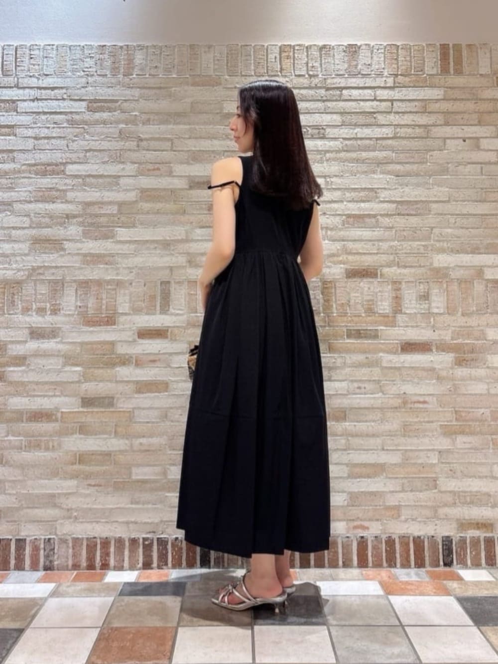 シルバー系のパンプス、ブラック系のワンピース、ブラック系のショルダーバッグを着用したレディースの夏コーディネートの4枚目の写真