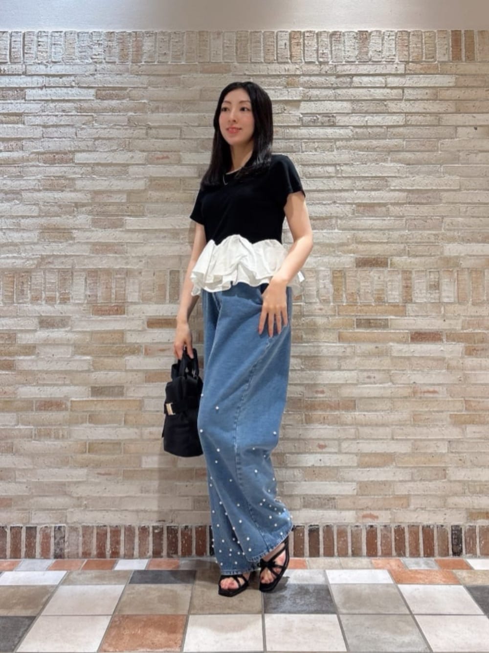 ブラック系のパンプス、ブラック系のTシャツ/カットソー、ブルー系のデニムパンツを着用したレディースの夏コーディネートの2枚目の写真