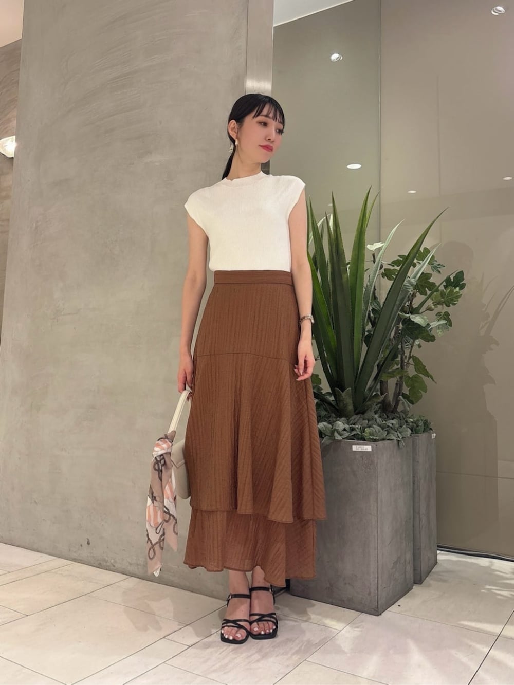 ホワイト系のショルダーバッグ、ブラウン系のスカート、ホワイト系のニット/セーターを着用したレディースの夏コーディネートの3枚目の写真