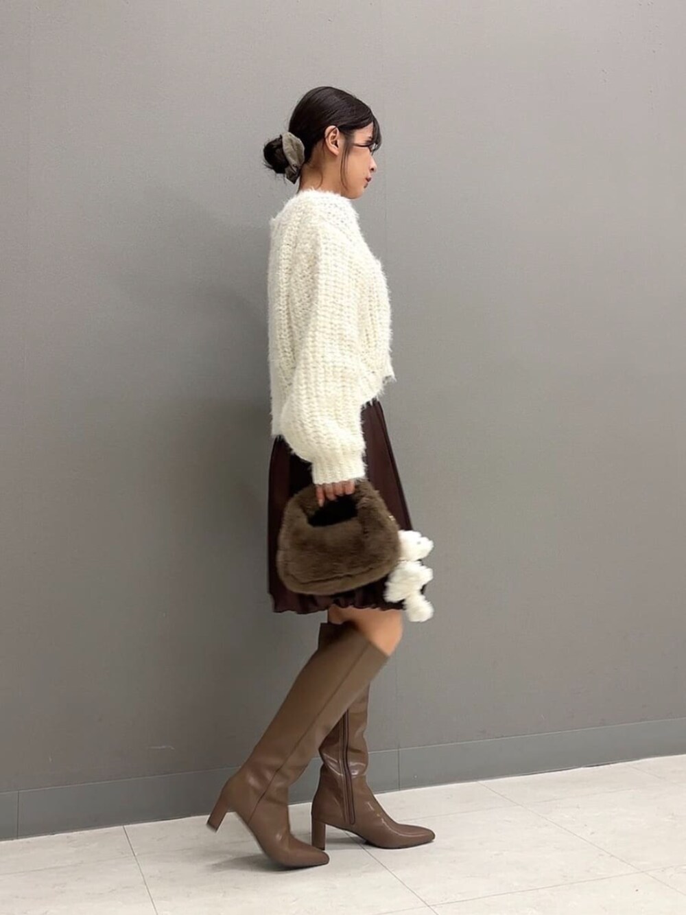 ブラウン系のブーツ、ブラウン系のハンドバッグ、ホワイト系のニット/セーターを着用したレディースの秋コーディネートの3枚目の写真