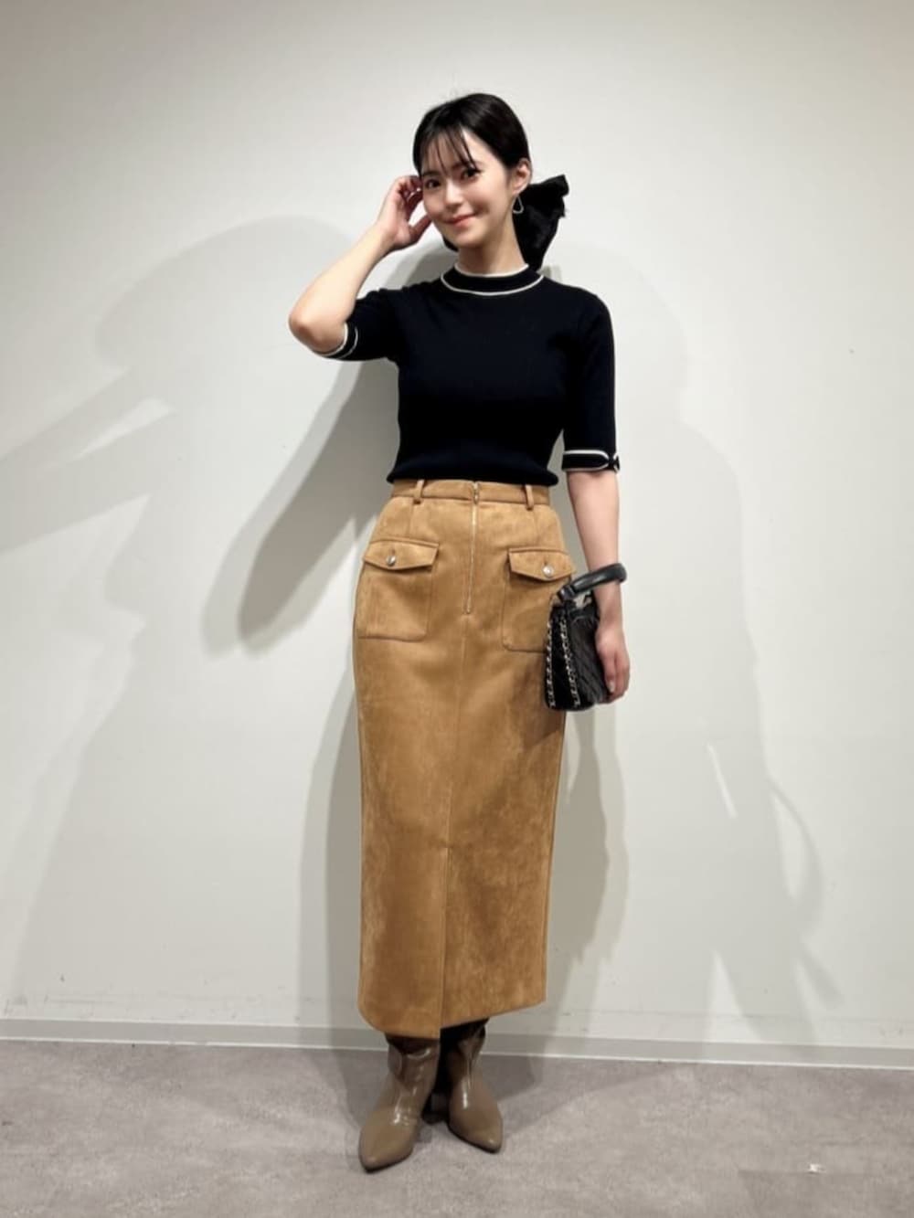 ブラック系のニット/セーター、ベージュ系のスカート、ブラウン系のブーツを着用したレディースの秋コーディネートの3枚目の写真