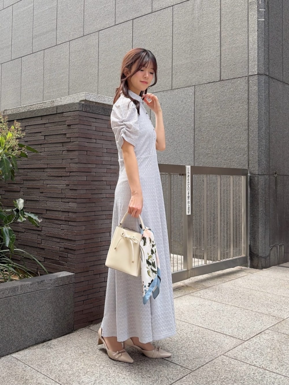 ベージュ系のパンプス、グレー系のワンピース、ホワイト系のショルダーバッグを着用したレディースの春コーディネートの2枚目の写真