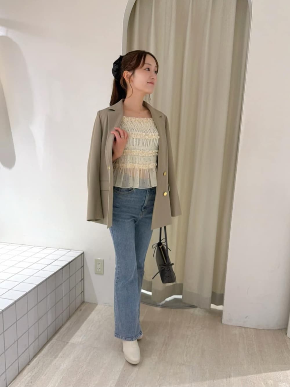 ブルー系のデニムパンツ、ホワイト系のシャツ/ブラウス、ブラウン系のショルダーバッグを着用したレディースの秋コーディネートの2枚目の写真