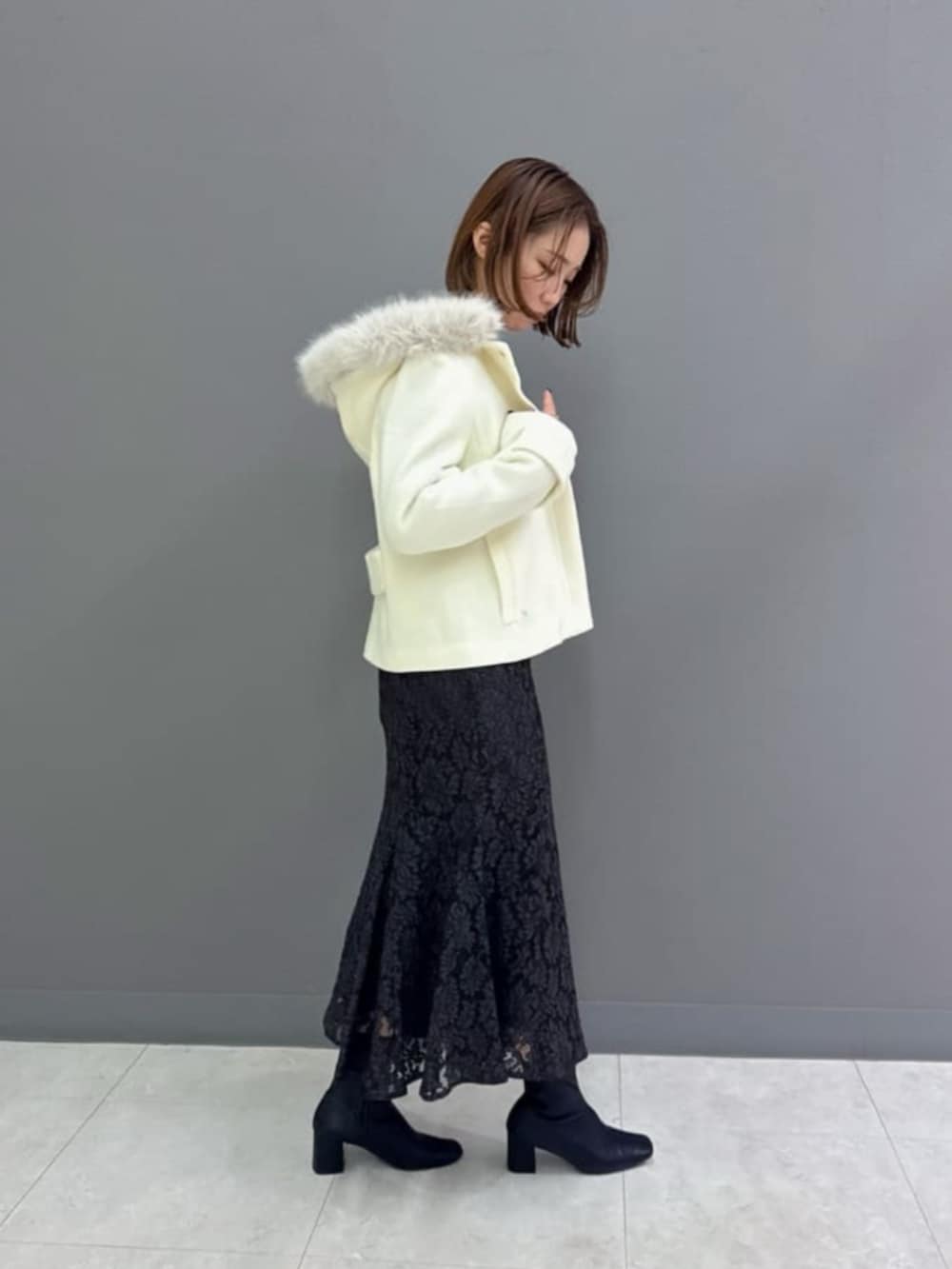 ホワイト系のブルゾン、グレー系のニット/セーター、グレー系のスカートを着用したレディースの冬コーディネートの3枚目の写真