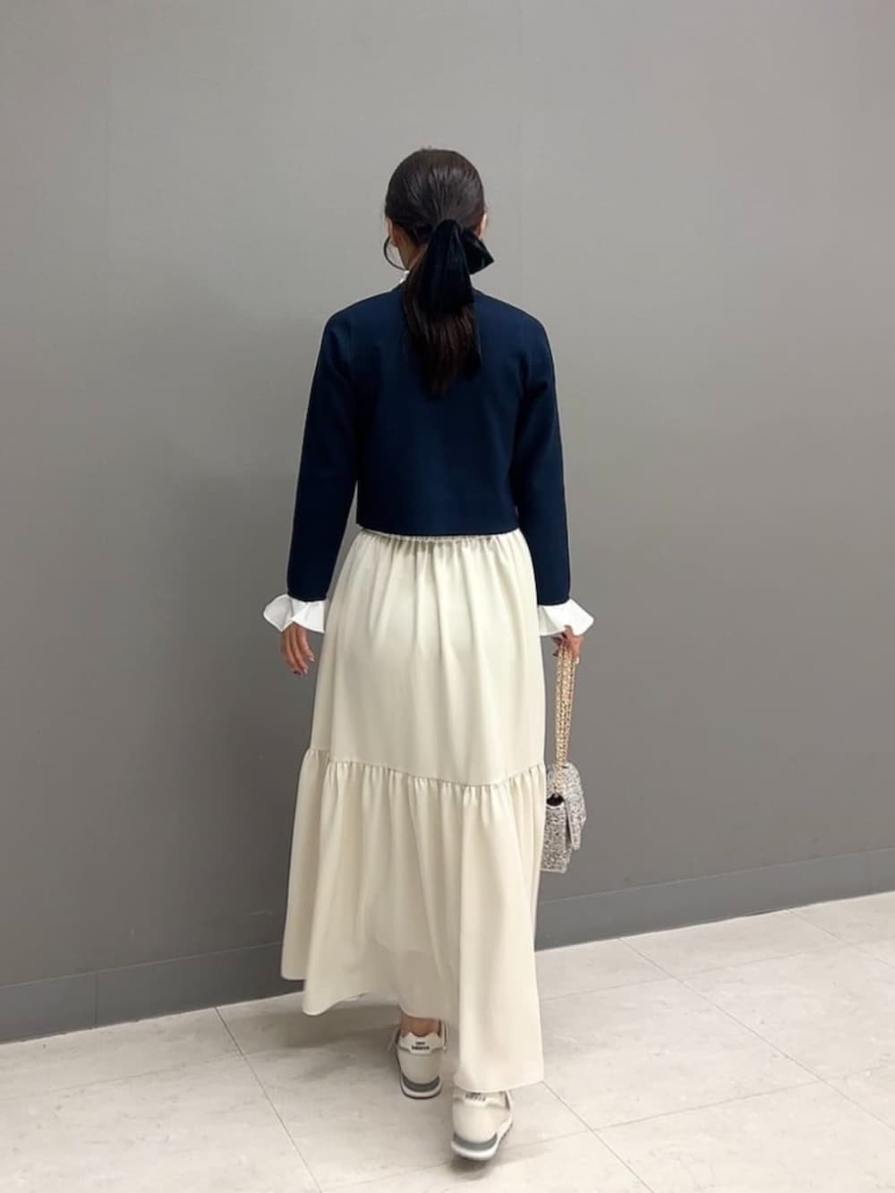 ブルー系のカーディガン/ボレロ、ホワイト系のスカート、ブラック系のショルダーバッグを着用したレディースの春コーディネートの3枚目の写真