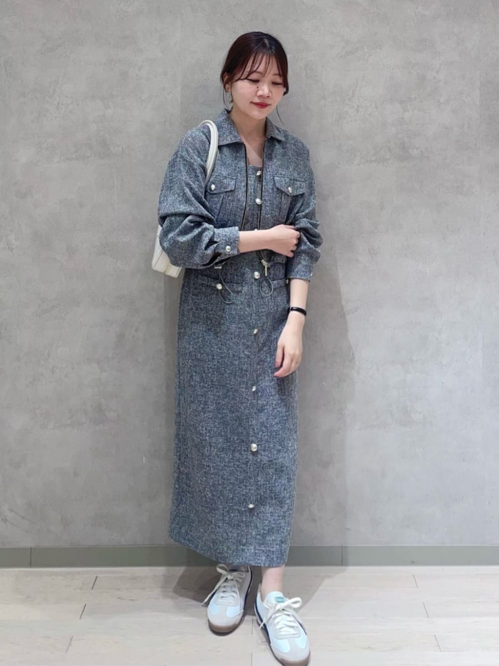 ホワイト系のショルダーバッグ、ブラック系のブルゾン、ブラック系のジャンパースカートを着用したレディースの春コーディネートの3枚目の写真