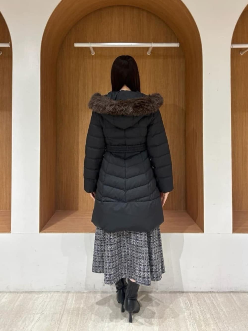 ブラック系のダウンジャケット/コート、ホワイト系のニット/セーター、ブラック系のスカートを着用したレディースの冬コーディネートの3枚目の写真