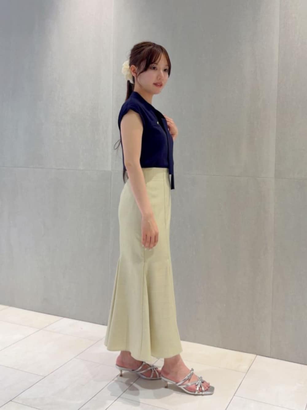 シルバー系のパンプス、ブルー系のニット/セーター、イエロー系のスカートを着用したレディースの夏コーディネートの2枚目の写真
