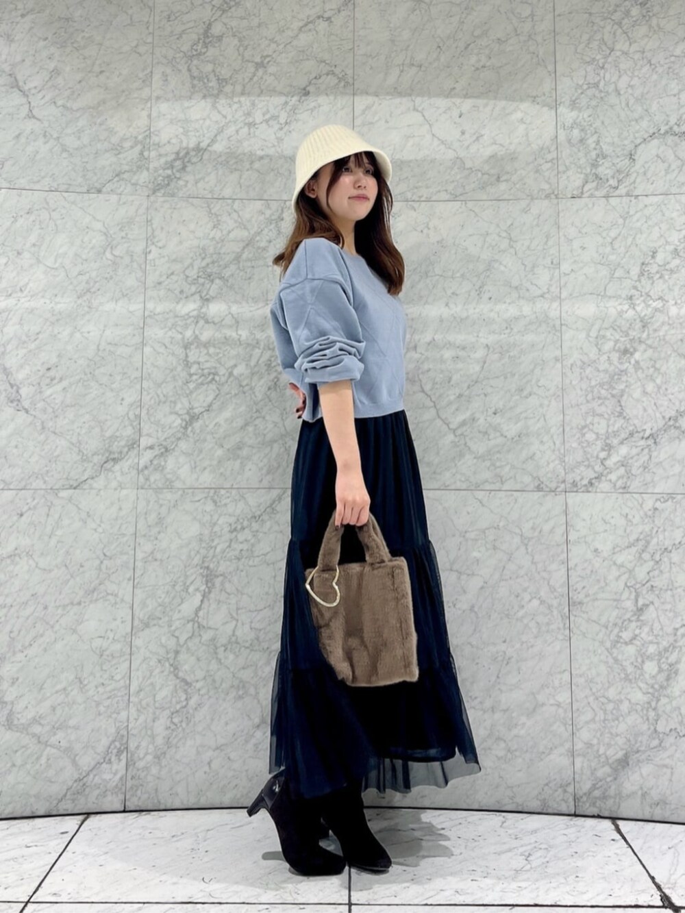 ブルー系のニット/セーター、ブラック系のスカート、ブラウン系のトートバッグを着用したレディースの秋コーディネートの2枚目の写真