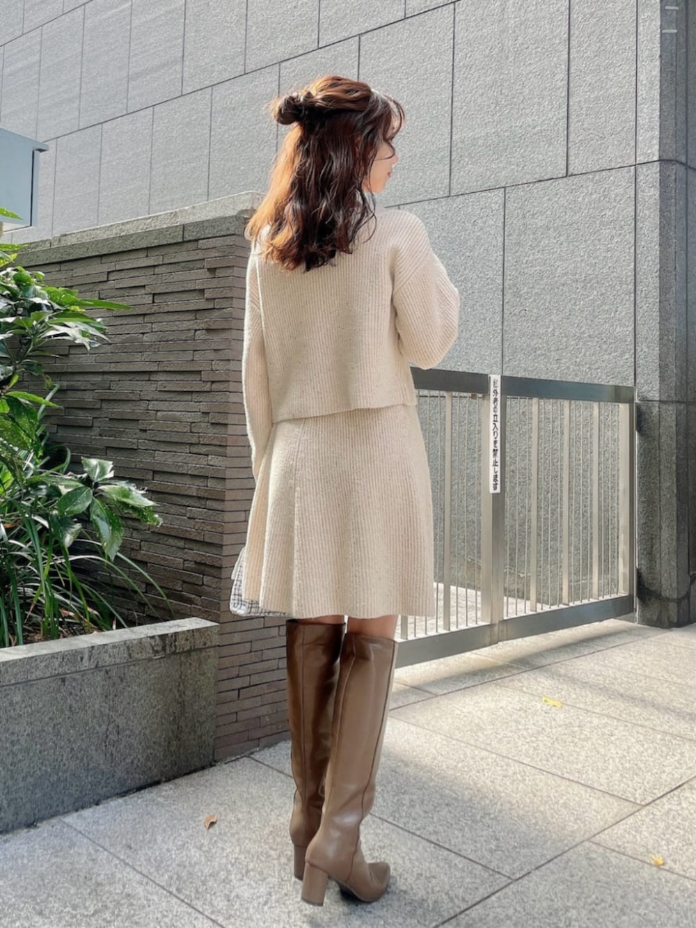 ホワイト系のショルダーバッグ、ブラウン系のブーツ、ベージュ系のワンピースを着用したレディースの冬コーディネートの2枚目の写真