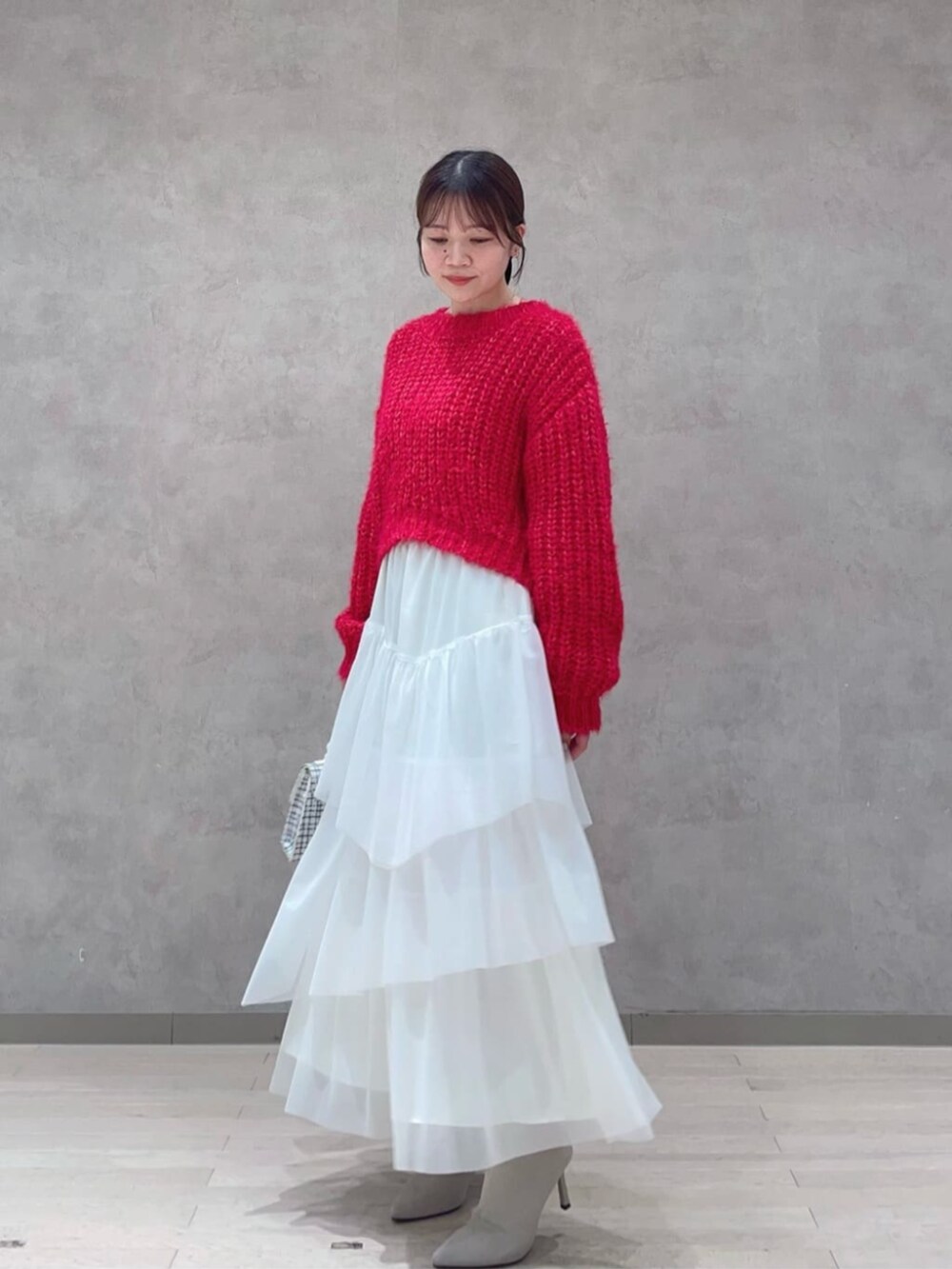 ホワイト系のショルダーバッグ、レッド系のニット/セーター、ホワイト系のスカートを着用したレディースの秋コーディネートの2枚目の写真